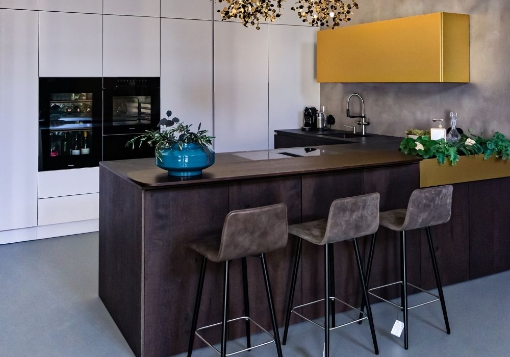 Küche mit brauner Kochinsel, gelben Regalelementen und stilvollen Dekorationen – Wohnatelier im Schlossquartier in Eisenstadt